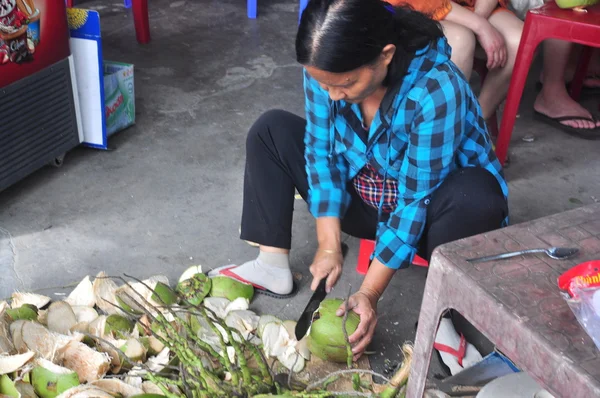 Nha Trang, Vietnam - 7 febbraio 2016: Una donna vietnamita sta tagliando la noce di cocco ai viaggiatori su un venditore di alberi — Foto Stock
