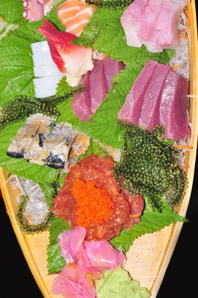 Um barco de sushi com atum, salmão, caviar verde e polvo — Fotografia de Stock