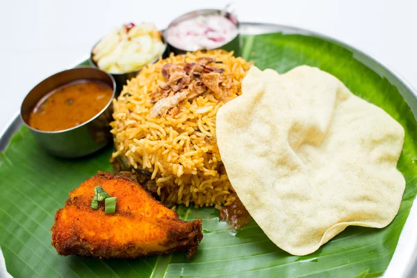 Indian meal with fish and fried rice on banana leaf tray