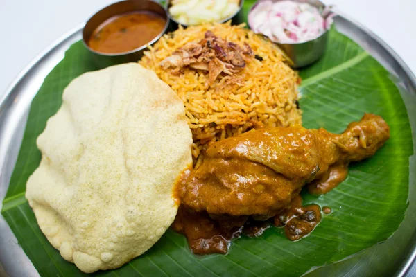 Indian meal with curry chiken and plain rice on banana leaf tray