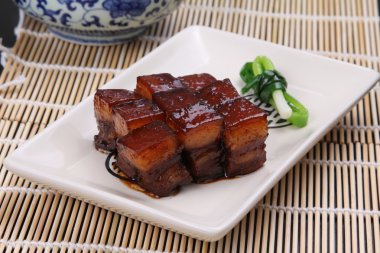 Stewed pork meat in chinese style on white plate on bamboo tray clipart