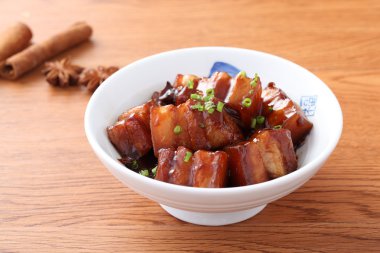 Stewed meat of pork in chinese style in white bowl in wooden tab clipart