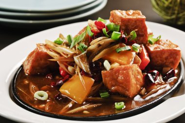 Soğan ve beyaz plaka üzerinde soslar Kızarmış tofu