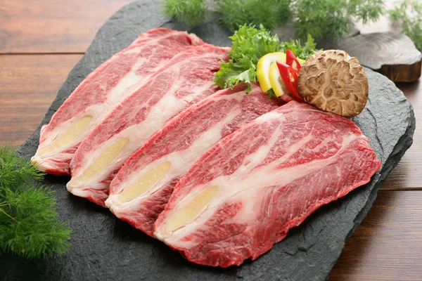 Carne fresca en rodajas en plato de piedra con champiñones y limón — Foto de Stock