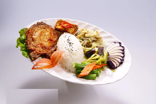 Memanggang daging babi panggang dengan sayuran di piring putih di belakang putih — Stok Foto