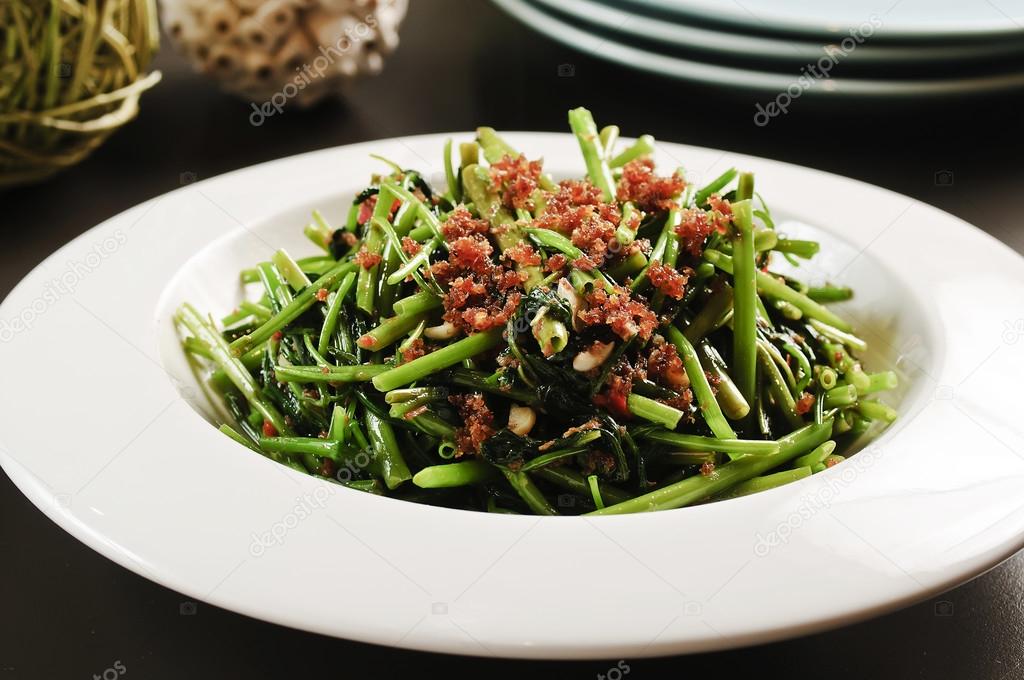 Fried vegetables of the morning glory or rau muong on white plat
