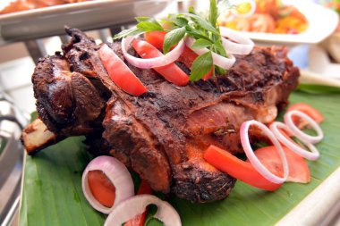 Biber, soğan ve muz lea üzerinde otlar ile bütün kızarmış kuzu