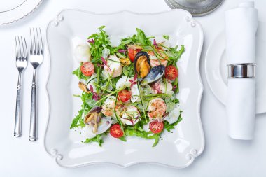Deniz ürünleri istiridye, karides, kalamar, marul, domates salatası ve 