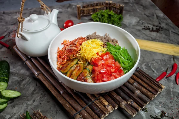 Fideos coreanos con kimchi, tomates, chile en un tazón blanco sobre bambú — Foto de Stock