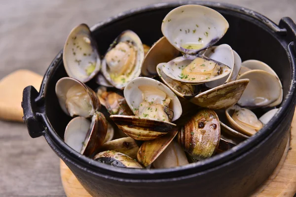 Knoflook, witte wijn clam in zwarte pot op houten dienblad in Aziatische rest — Stockfoto