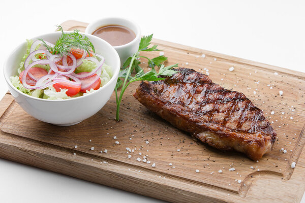 New York steak with vegetable salad on wooden cutting board