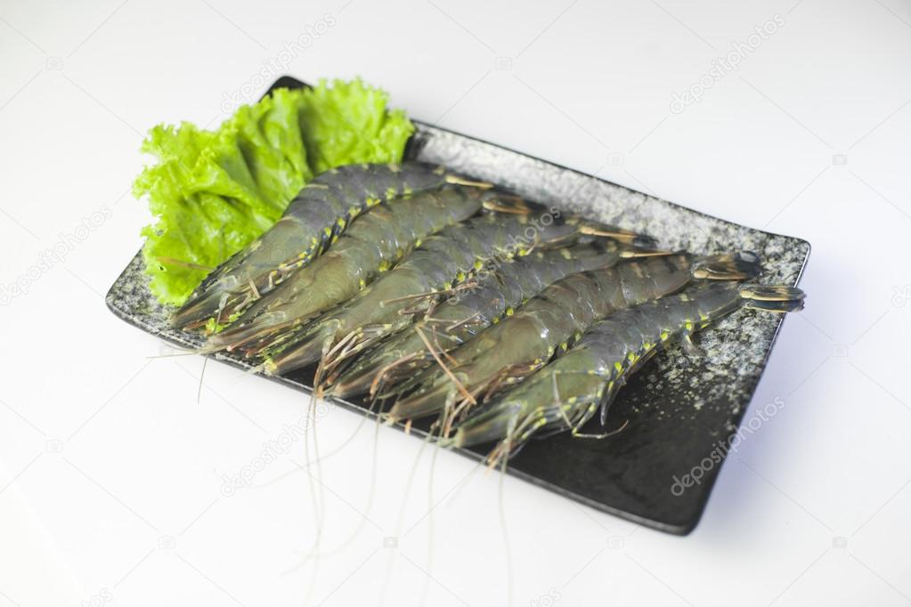 Fresh tiger shrimp with lettuce on black plate on white backgrou