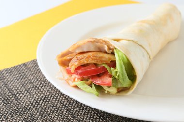 Kebap şal beyaz tabakta domates ve marul ile rulo