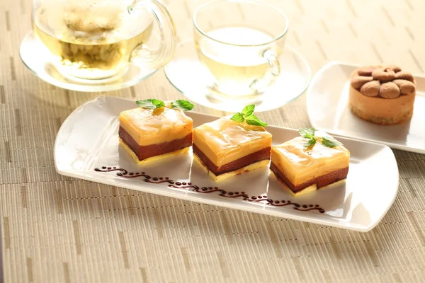 Pastel de pudín con hojas de menta en plato blanco con té — Foto de Stock