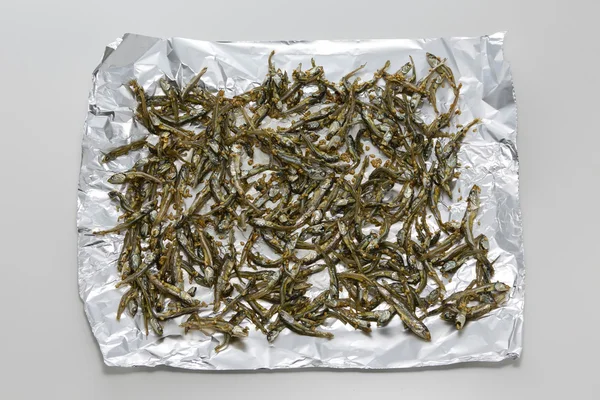 Fried dried anchovy fish on aluminum paper in asia — Stock Photo, Image