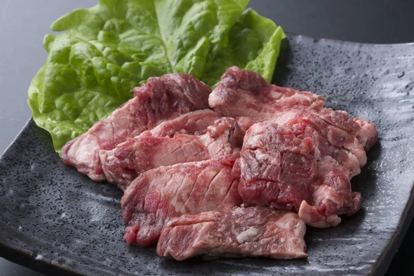 Carne roja Haramisuji de bovino con lechuga en plato negro — Foto de Stock