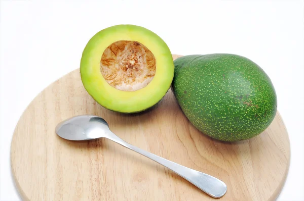 Avocado op de snijplank met lepel op een witte achtergrond — Stockfoto