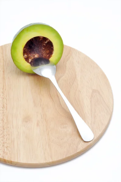 Avocado op de snijplank met lepel op een witte achtergrond — Stockfoto