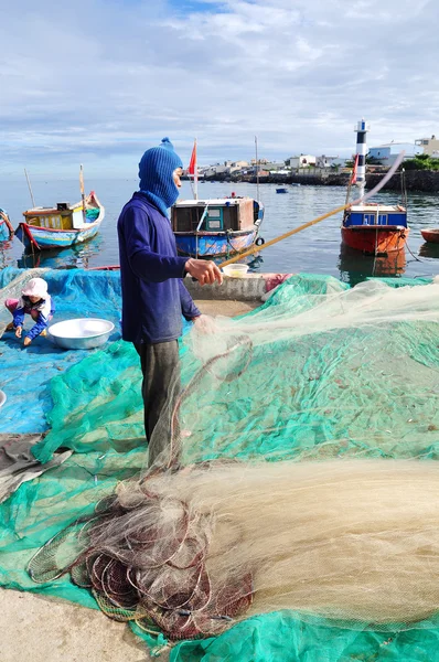 Quang Ngai, Vietnam - 31 de julio de 2012: Un viejo pescador está retirando anchoas de su red de pesca para comenzar una nueva jornada de trabajo en la isla de Ly Son —  Fotos de Stock