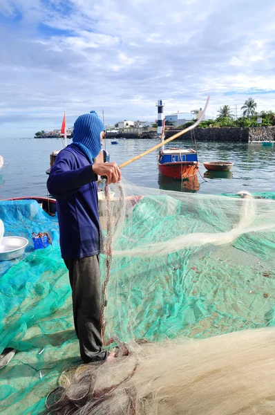 Quang Ngai, Vietnam - 31 Temmuz 2012: Eski bir balıkçı Hamsi balığı Ly oğlu adasında yeni bir iş günü başlayacak onun balık ağı üzerinden kaldırıyor