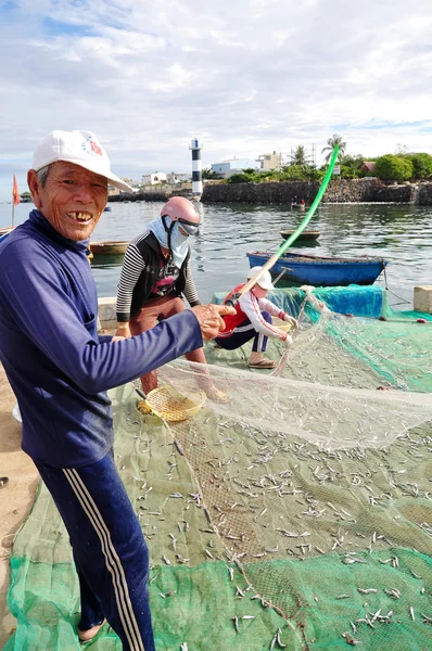 Quang Ngai, Vietnam - 31 Temmuz 2012: Eski bir balıkçı Hamsi balığı Ly oğlu adasında yeni bir iş günü başlayacak onun balık ağı üzerinden kaldırıyor — Stok fotoğraf