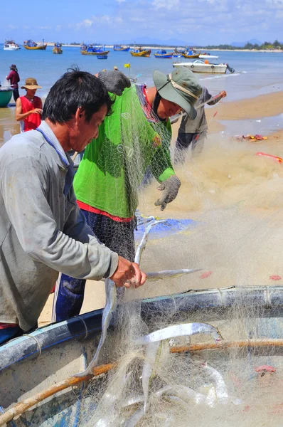 Lagi, Vietnam - 26 de febrero de 2012: Los pescadores locales están retirando peces de sus redes de pesca en la playa de Lagi —  Fotos de Stock