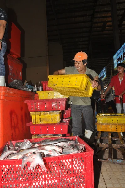 Ho Chi Minh City, Vietnam - 28 de noviembre de 2013: Los porteros están trabajando duro para cargar muchas cestas de pesca en el mercado de mariscos nocturnos al por mayor Binh Dien, el más grande de Vietnam — Foto de Stock