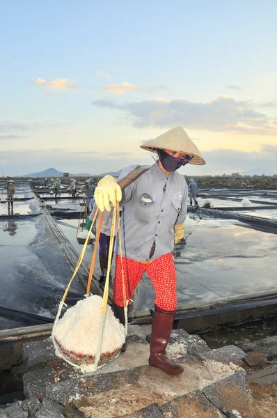 Ninh Hoa, Vietnam - March 2, 2012: Vietnamese women are burdening hard to collect salt from the extract fields to the storage fields — Stock Photo, Image