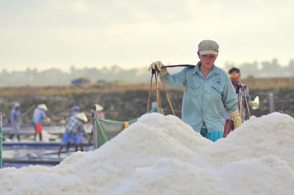 Ninh Hoa, Vietnam - March 2, 2012: Vietnamese women are burdening hard to collect salt from the extract fields to the storage fields — Stock Photo, Image