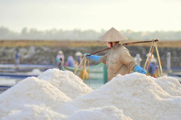 Ninh Hoa, Vietnã - 2 de março de 2012: Mulheres vietnamitas estão sobrecarregando duro para coletar sal dos campos de extração para os campos de armazenamento — Fotografia de Stock