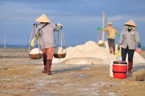 Ninh Hoa, Vietnã - 2 de março de 2012: Mulheres vietnamitas estão sobrecarregando duro para coletar sal dos campos de extração para os campos de armazenamento — Fotografia de Stock