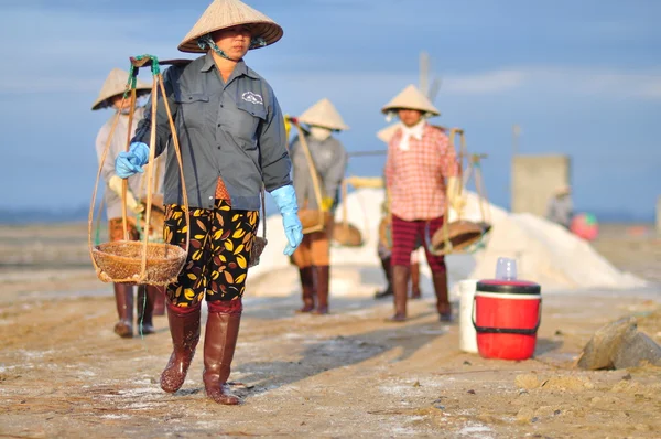 Ninh Hoa, Vietnam - 2 marzo 2012: Le donne vietnamite stanno gravando duramente per raccogliere il sale dai campi di estrazione ai campi di stoccaggio — Foto Stock