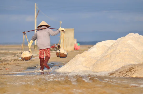 Ninh Hoa, Vietnã - 2 de março de 2012: Mulheres vietnamitas estão sobrecarregando duro para coletar sal dos campos de extração para os campos de armazenamento — Fotografia de Stock