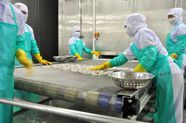 Phan Rang, Vietnam - 29 de diciembre de 2014: Los trabajadores están organizando camarones en línea con la máquina de congelación en una fábrica de mariscos en Vietnam — Foto de Stock