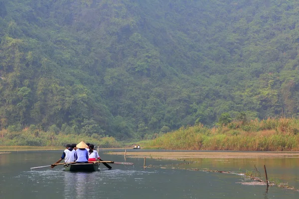 Ninh Binh, Vietnam - March 29, 2010: Ferrymen are taking tourists to visit the Trang An Eco-Tourism Complex, a complex beauty - landscapes called as an outdoor geological museum — Stock Photo, Image