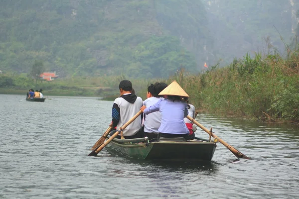 Ninh Binh, Vietnam - March 29, 2010: Ferrymen are taking tourists to visit the Trang An Eco-Tourism Complex, a complex beauty - landscapes called as an outdoor geological museum — Stock Photo, Image