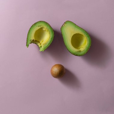 Pembe arka planda avokado ısırığı. Düz yatıyordu