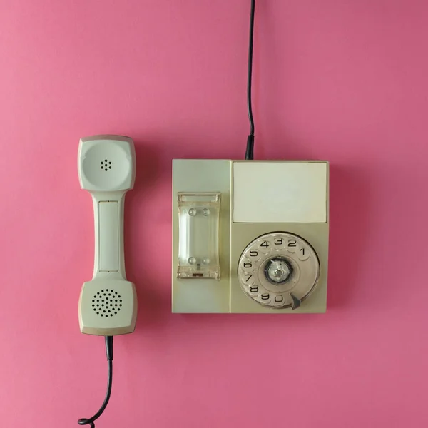 Pembe arka planda eski gri bir telefon. Düz yatıyordu