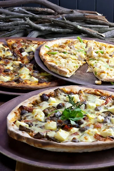 Tres pizzas en mesa de madera rústica — Foto de Stock