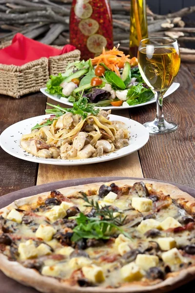 Restaurant-Mahlzeit mit Pizza, Pasta, Salat und Getränken — Stockfoto