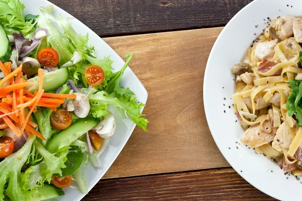 Nudeln mit Hühnchen und Gemüsesalat auf dem Tisch — Stockfoto