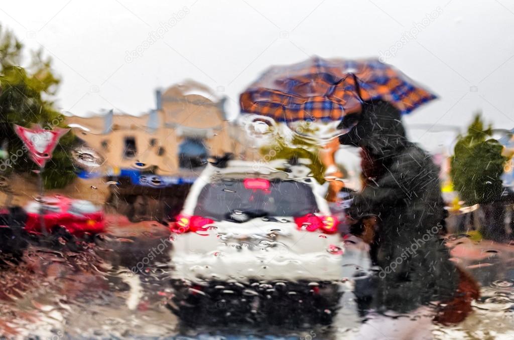 Woman with umbrella crossing streen in rain storm
