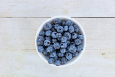 Doğal arka planda beyaz kasede yaban mersini.