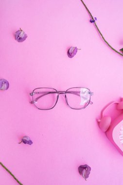 Resimde beş köşeli gözlük var. Pastel pembe arka planda, yaz tarzında. Alarmlı saat mor floş