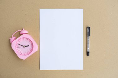 Beyaz kağıt, alarmlı saat ve kahverengi kağıt üzerine kalem. Minimalist Styl