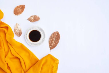 Sonbahar kompozisyonu. Bir fincan kahve, sarı eşarp, beyaz arka planda kuru yapraklar. Sonbahar, sonbahar konsepti. Düz konum, üst görünüm, boşluğu kopyala
