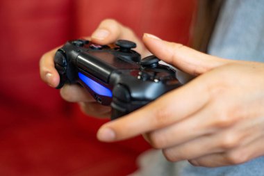 Video oyunu kumandası kullanan bir kadın, uzaktan kumandayı kullanan ve altını iten eller, mavi ışık