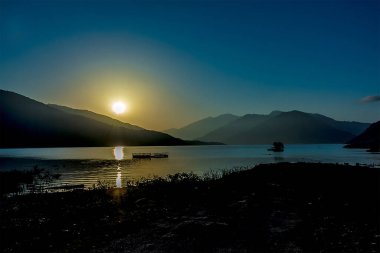  Vadide güzel bir gün batımı olan dağ manzarası, dramatik gökyüzü ve göl