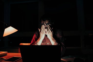 Stresli beyaz erkek, gece geç saatlere kadar çalışıp ev bilgisayarındaki görevleri tamamlıyor.