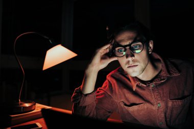 Gece geç saatlerde laptopta çalışan beyaz erkek öğrenci teslim tarihlerine uymaktan yoruldu.